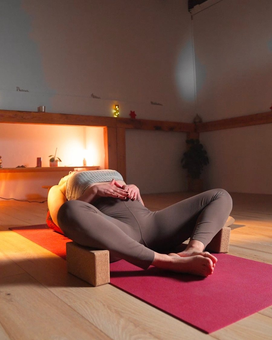 Posture de Yin Yoga allongée sur des blocs, mains posées sur le ventre
